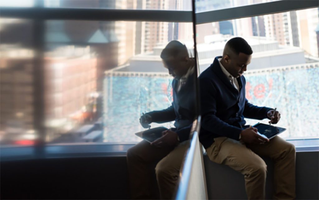 A man using a tablet, sitting by a window